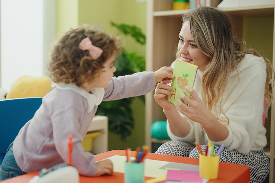 teacher-toddler-sitting-table-having-language-lesson-kindergarten
